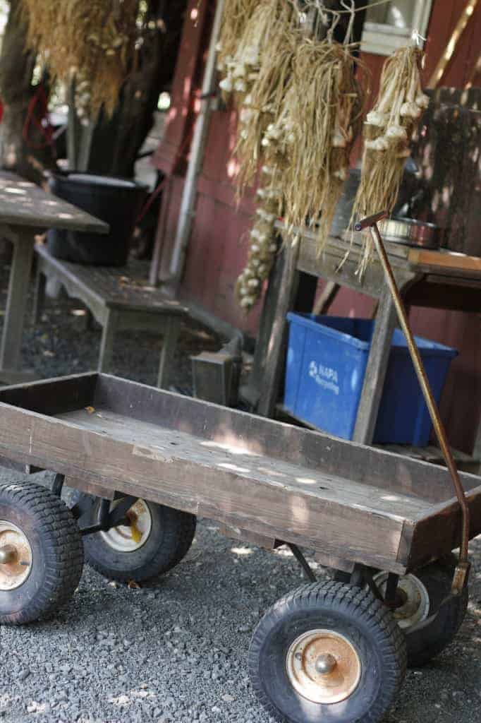 a wooden wagon sits in front of a rustic red barn