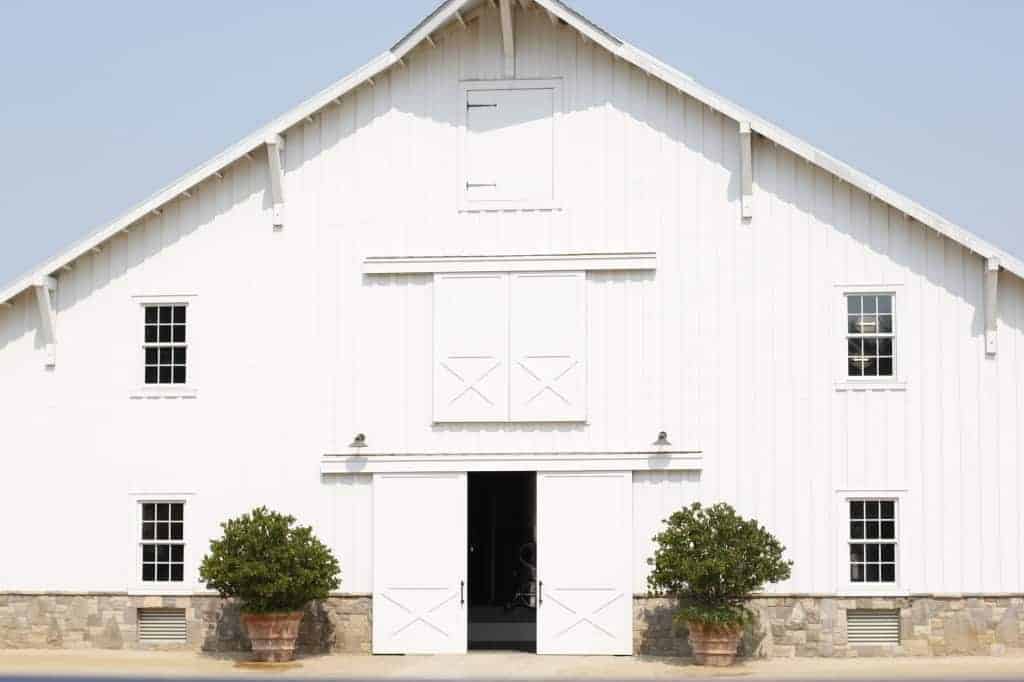 the exterior of a white rustic barn