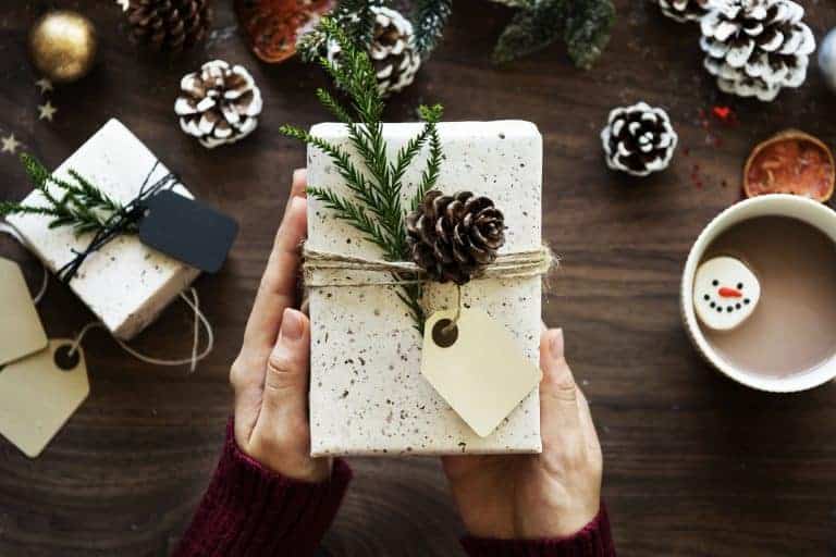 woman's hands holding a wrapped gift with winter decoration