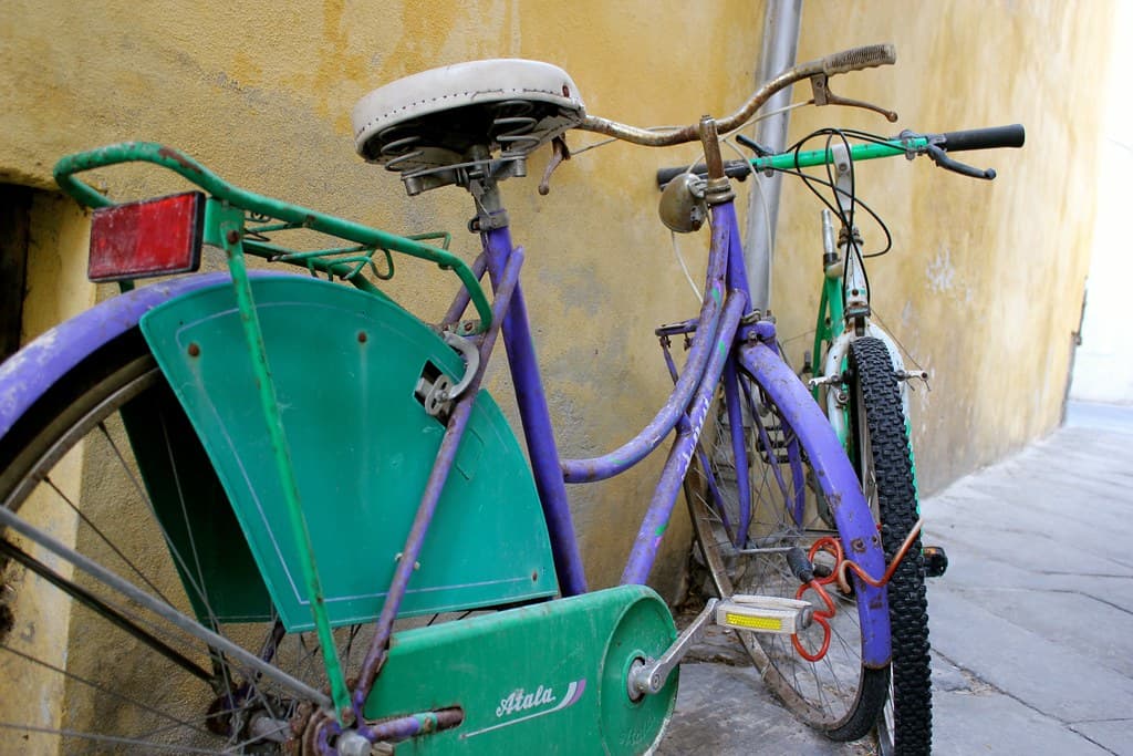 bicycle rests on the wall of a building in lucca