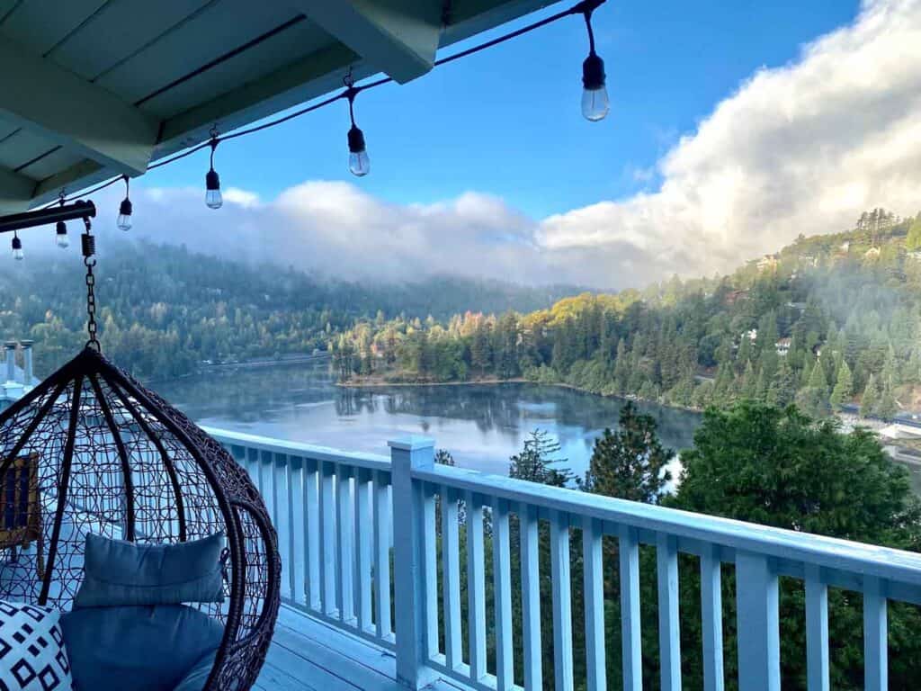 A deck with white wooden rails overlooks a scenic mountain lake