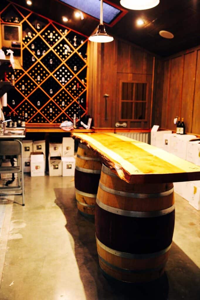 a bar made from two wine barrels and a piece of wood sits inside a wine cellar