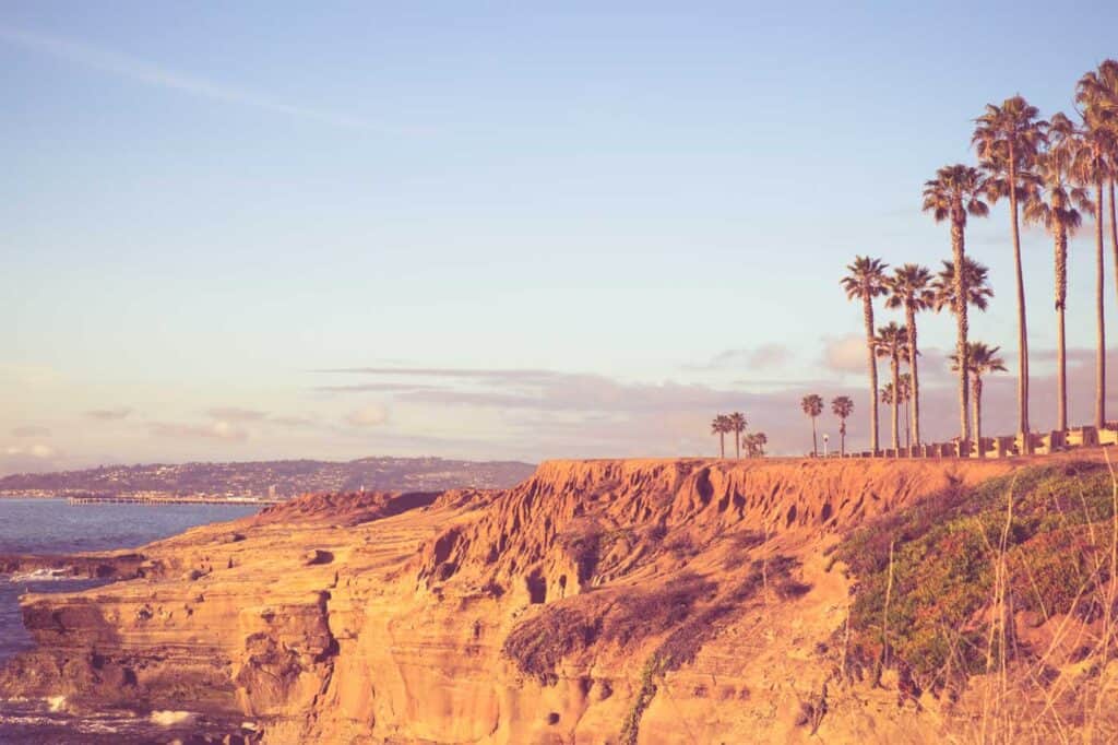 golden sandstone cliffs and palm trees at sunset