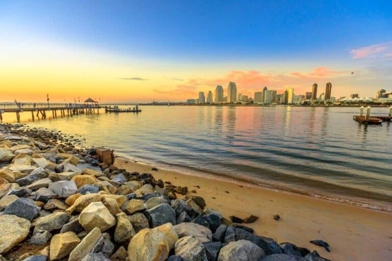 Scenic sunset on San Diego Bay from old wooden pier in Coronado Island, California. People and tourists fishing and walking and enjoying the view of the San Diego skyline downtown waterfront.