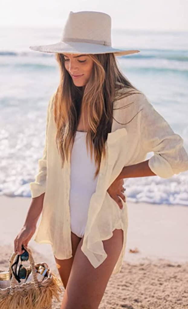 woman at the beach in a white long sleeve button down shirt