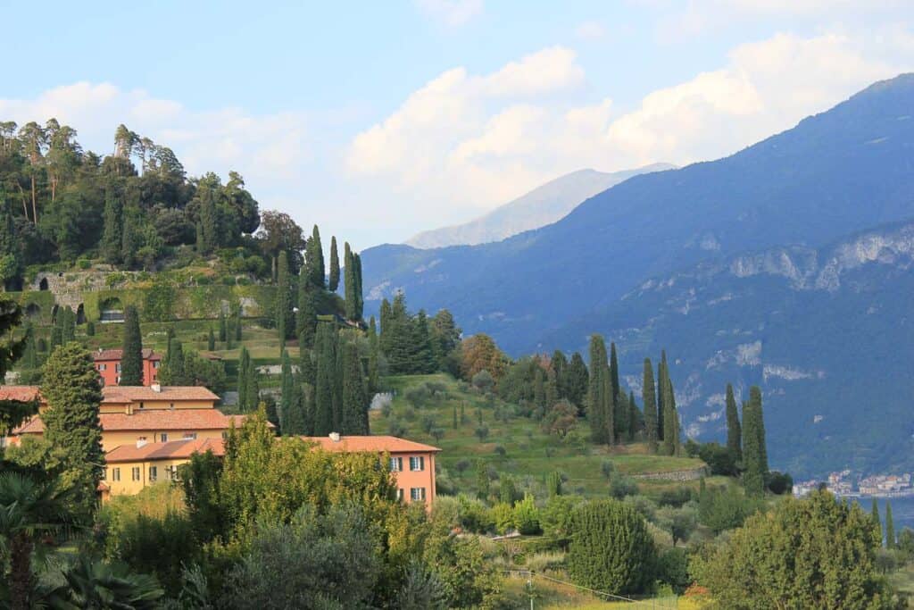 Blue mountains behind green hills that are dotted with orange buildings