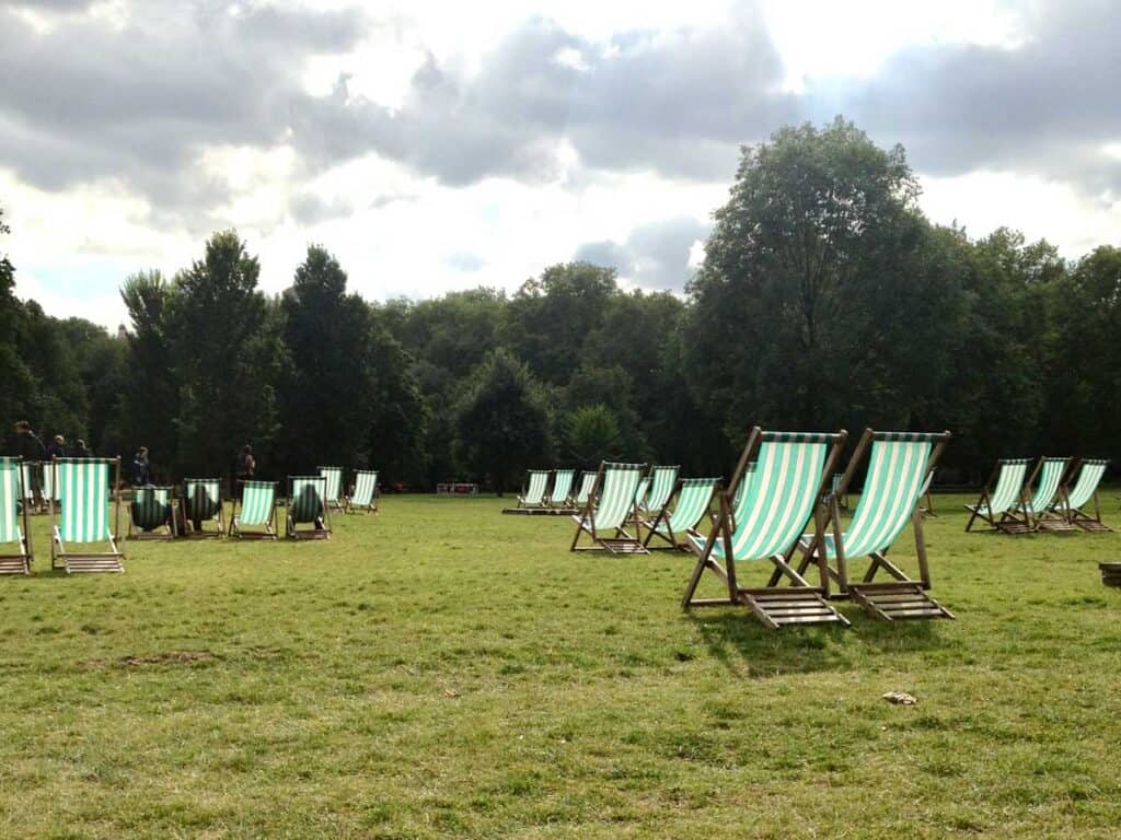 Green lawn chairs sit in pairs on a large green field