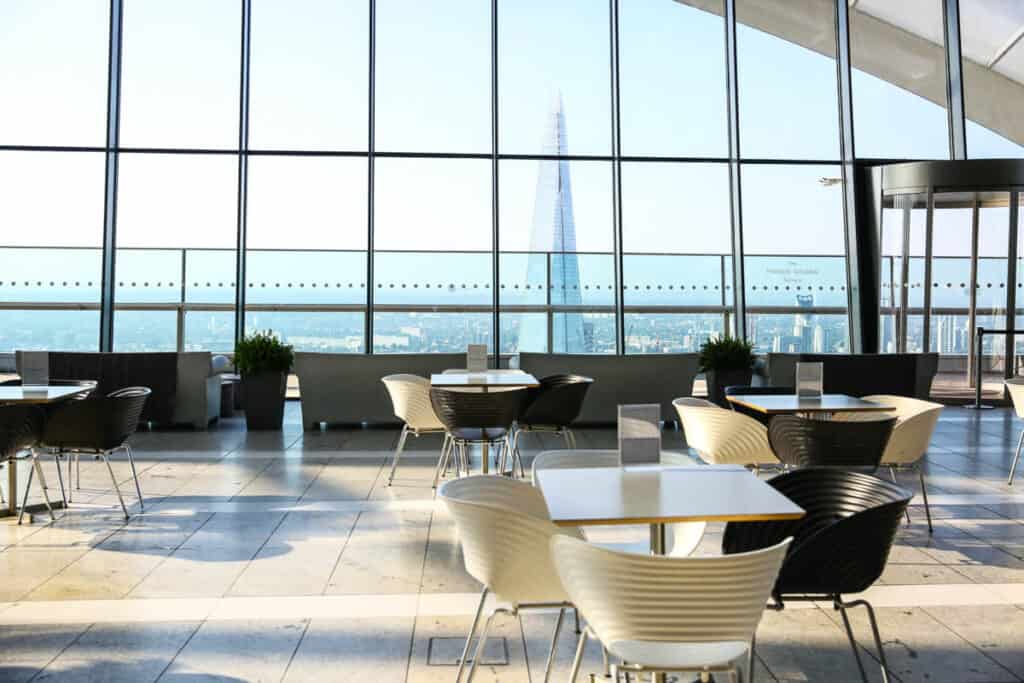 Dining table in a light filled atrium overlooks the skyline of London