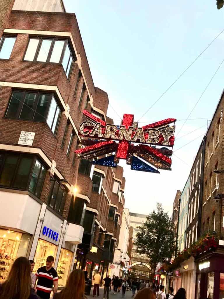 The Union Jack Flag hangs over a street filled with shops in London