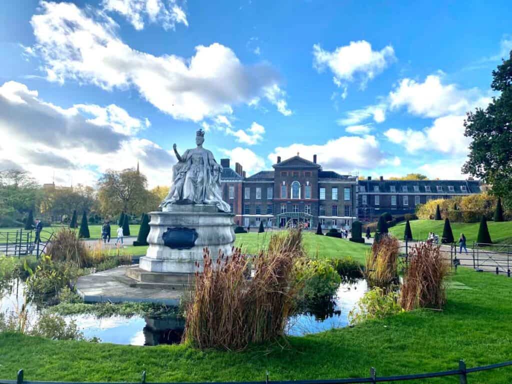 A status sits in front of the red brick Kensington Palace in London