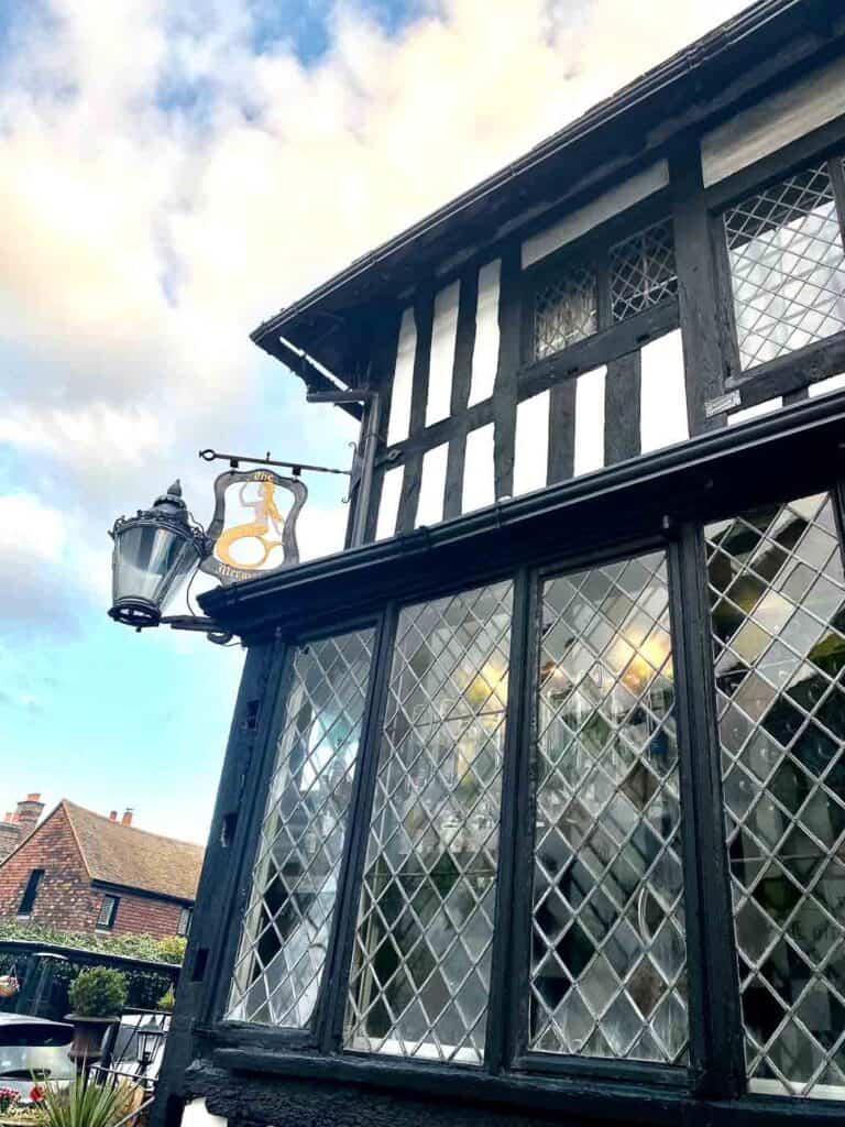 a sign for the mermaid inn hangs outside the tudor style building