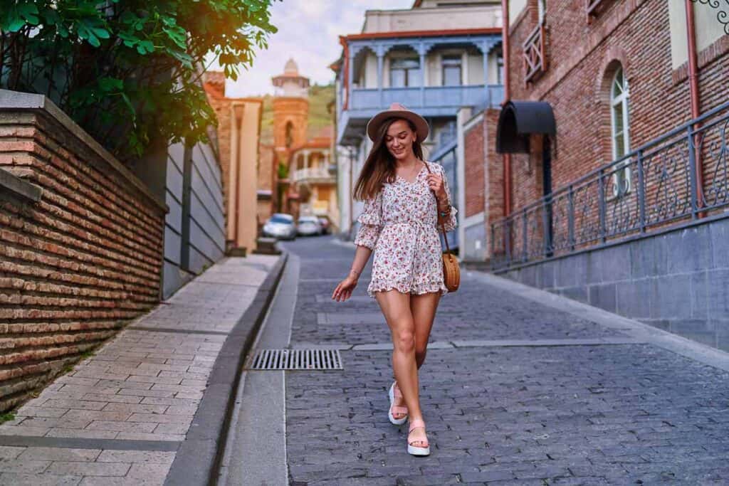 woman in a short one piece romper walking down a cobblestone street