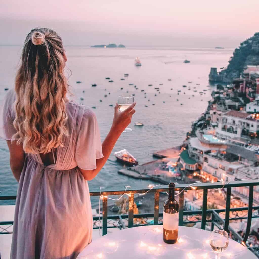 Woman standing on deck sipping drink.