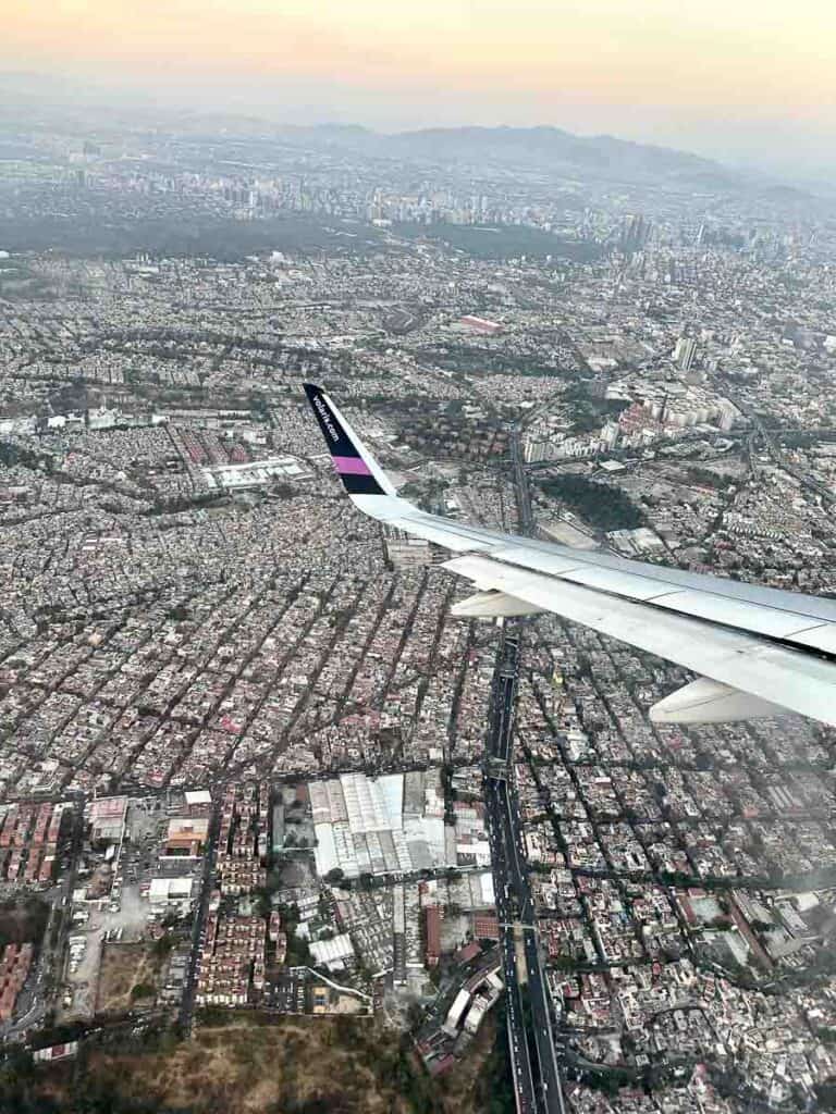 view of Mexico City from an airplane, with the wing of the plane in front