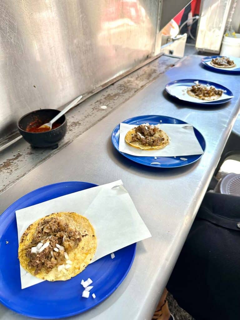 four blue plates in a line with one taco on each plate