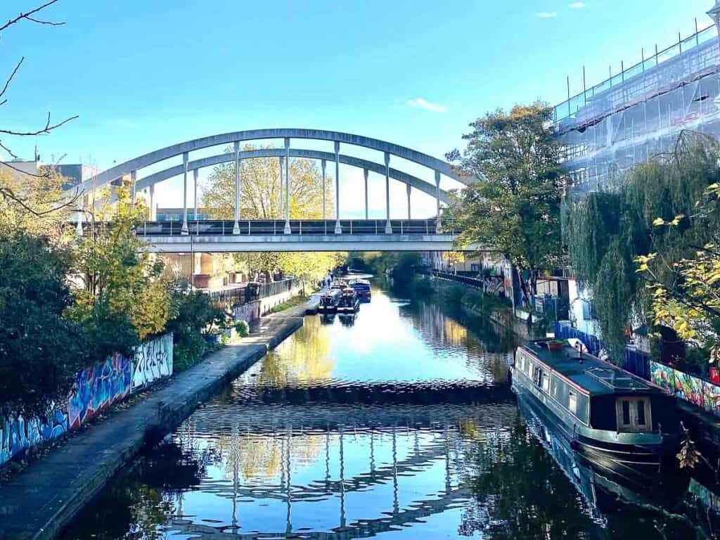 bridge over a canal in east london with a houseboat in the foreground