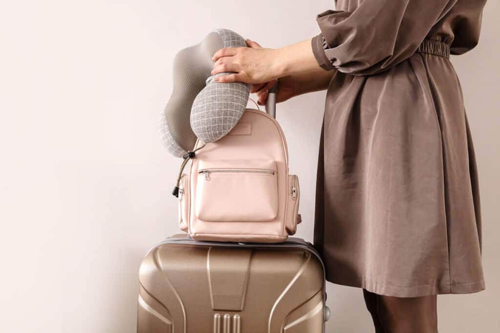 Closeup hands of travel woman holding backpack and stylish suitcase ready to business trip vacation isolated on white. Trendy female tourist getting ready to journey with baggage luggage