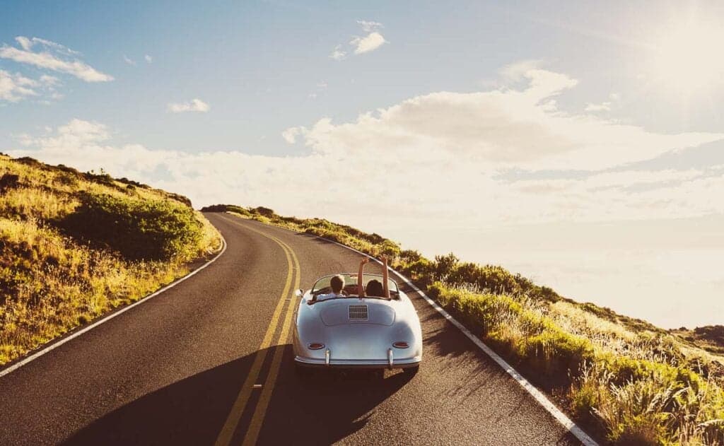 Happy Couple on a road trip on Country Road in Classic Vintage Sports Car