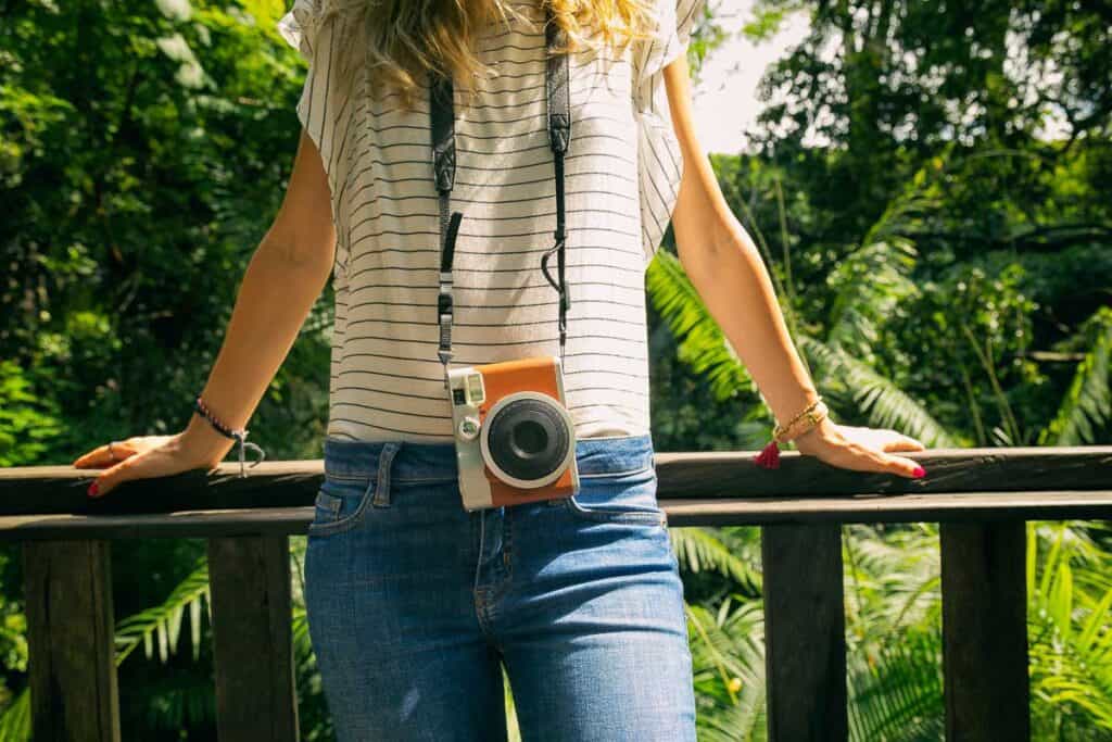 Modern fashionable woman posing with old camera in nature.